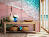 Pastel pink beach and teal ocean wave wallpaper with palm leaf accent