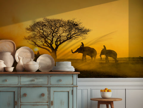 Elephants at sunset with a golden sky and tree silhouette, perfect for serene wall decor